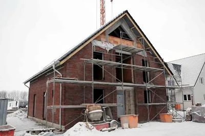 Rohbau eines Backsteinhauses mit Gerüst im Winter