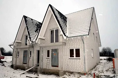 Helles Klinkerhaus mit zwei Giebeln im Rohbau, Schnee ringsum