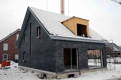 Haus mit dunkler Fassade und Dachgaube im Bau