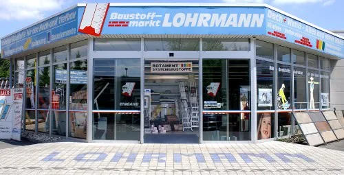 Außenansicht des Baustoffmarkts Lohrmann in Ahlen mit Glasfront und Schriftzug