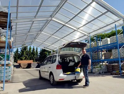 Überdachtes Hochregal mit Baustoffen und ein Auto, das beladen wird