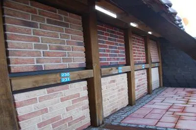 Klinkerriemchen in Rot- und Rosatönen an einer überdachten Musterwand, darunter Pflaster
