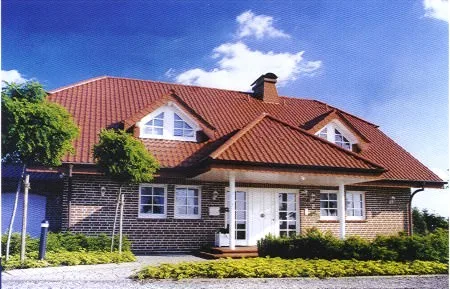Haus mit rotem Dach, dunkler Klinkerfassade und weißen Fenstern