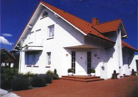 Weißes Haus mit rotem Dach, Balkon und Eingangstreppe