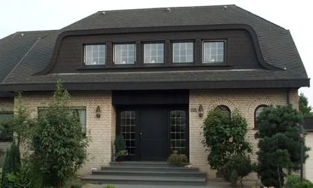 Haus mit dunklem Dach, heller Klinkerfassade und Eingangstreppe