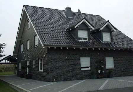 Haus mit dunkler Klinkerfassade und Gauben im dunklen Dach